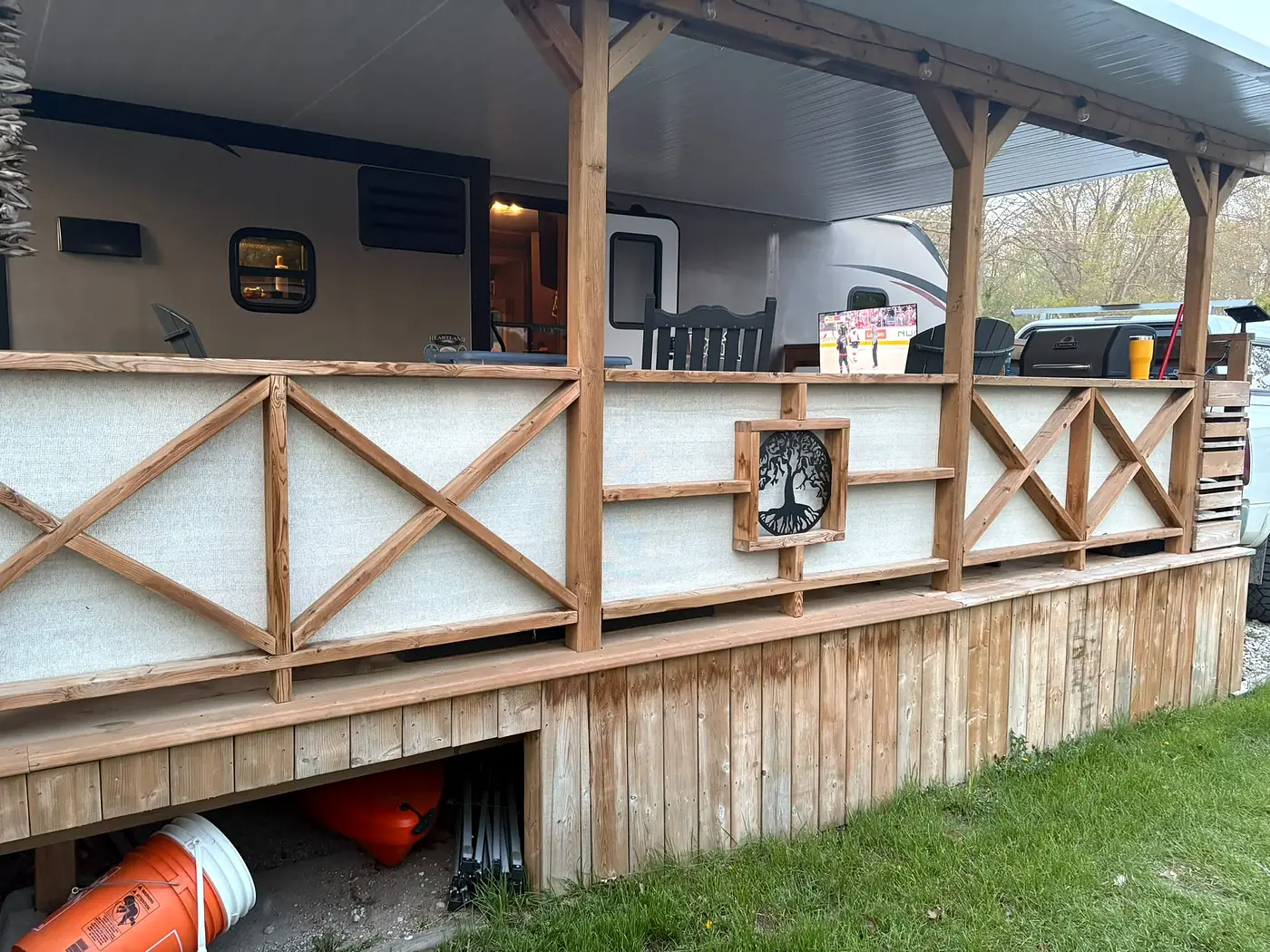 Covered porch with timber posts and a wooden railing built in a repeating X pattern