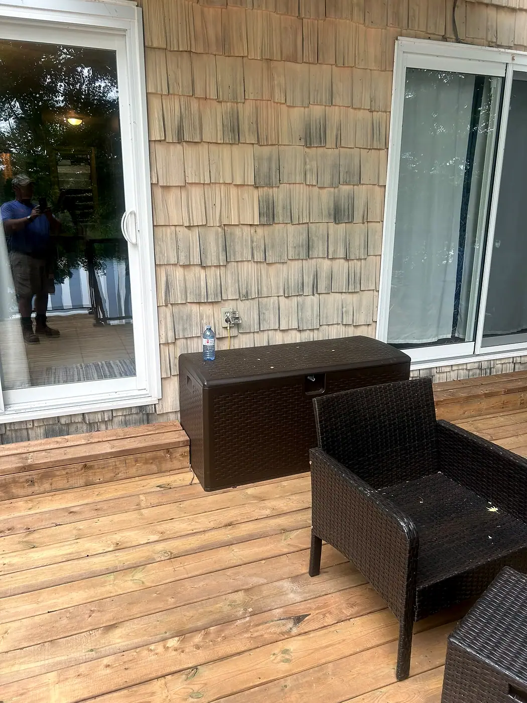 Wooden deck with patio furniture against a cedar-shingled house wall