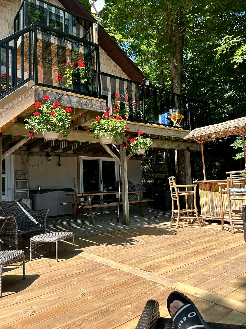 Two-level wooden deck with an upper balcony on timber posts, black railings and flower boxes