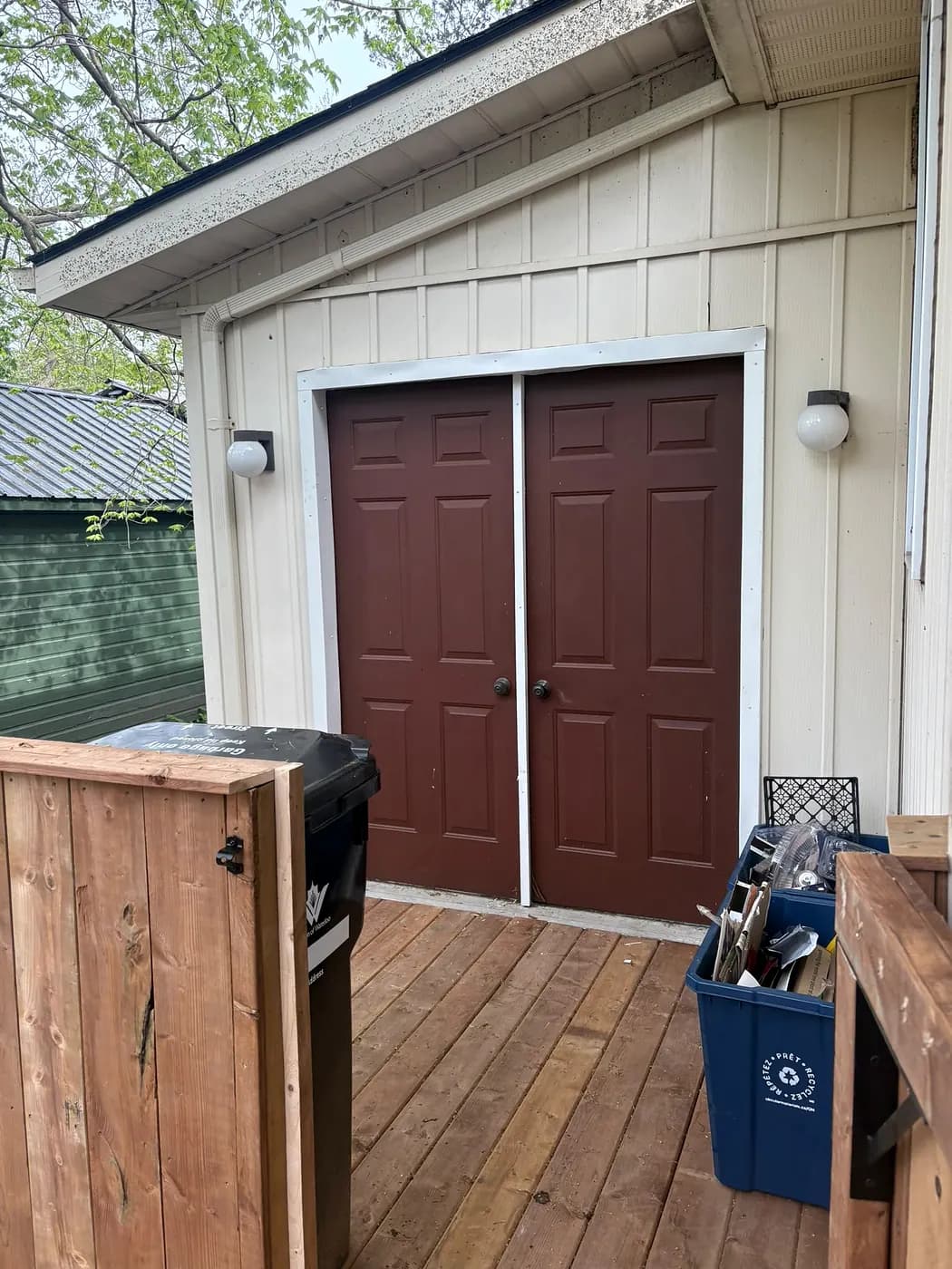 Wooden deck outside double doors with a tall cedar privacy screen at one corner