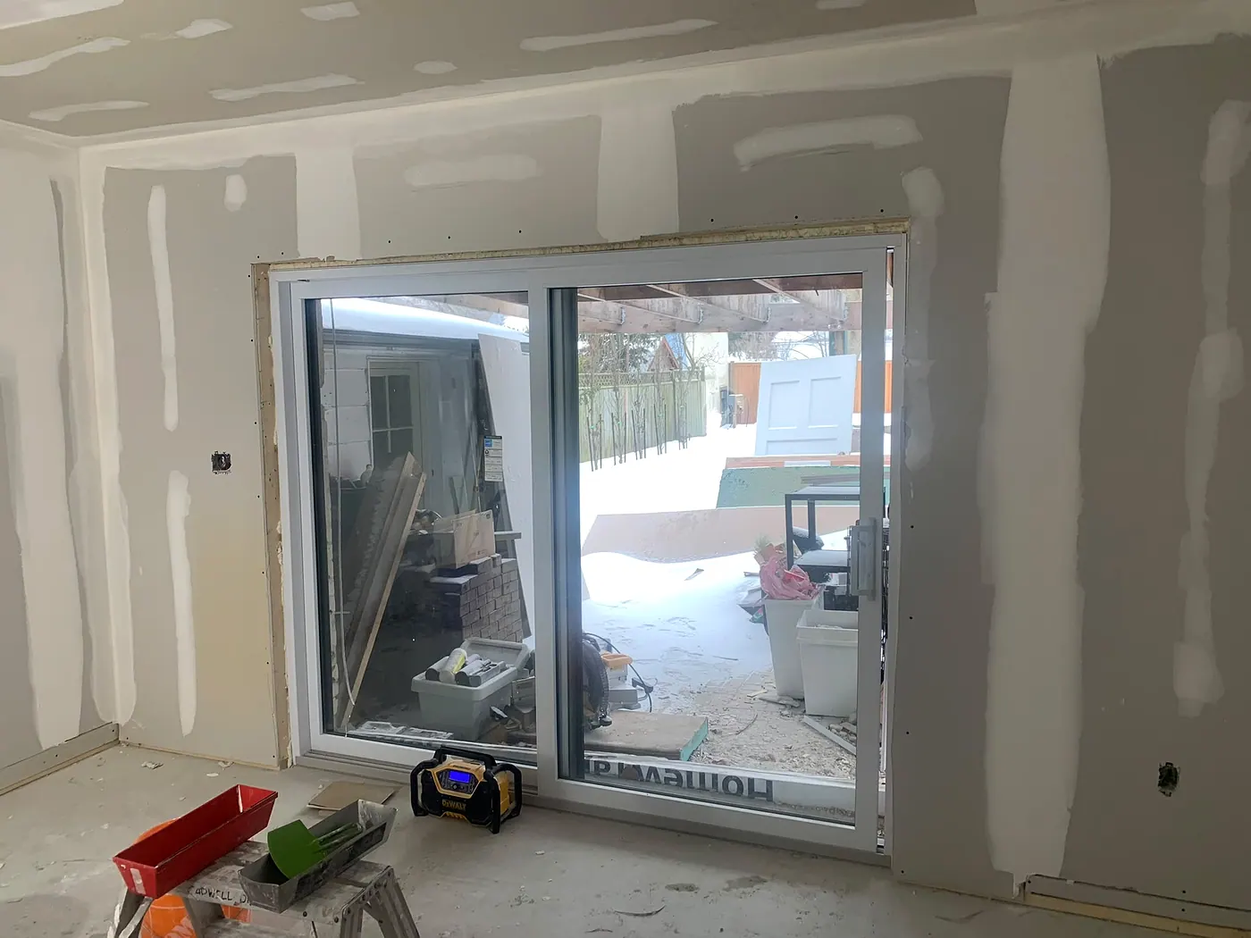 Newly drywalled room with taped seams around a large sliding patio door