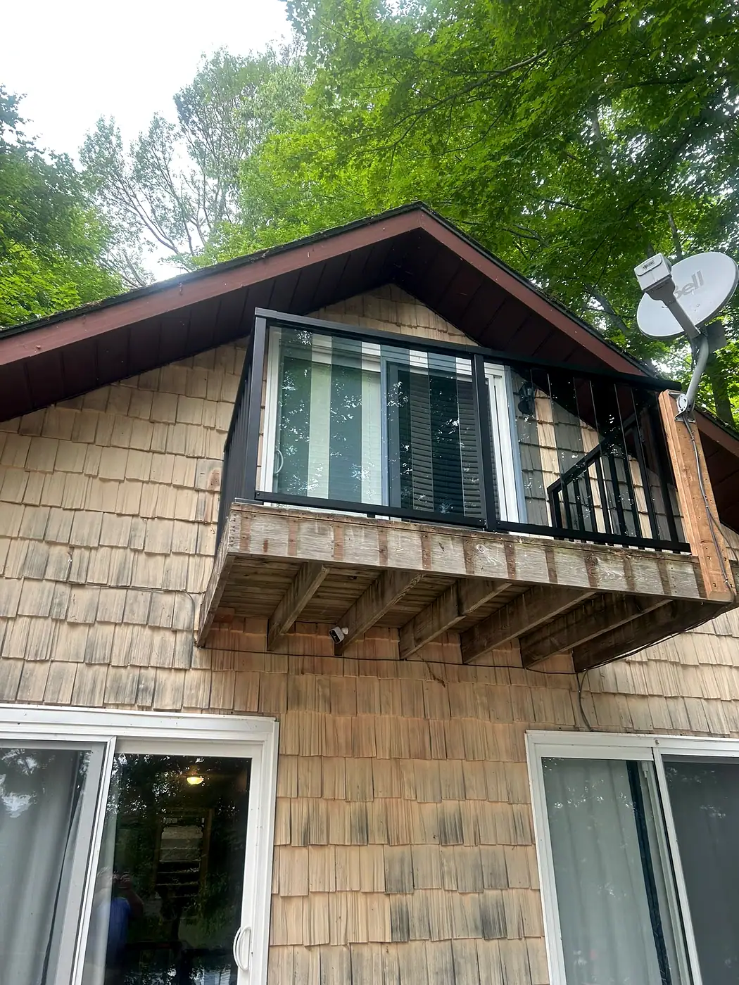 Cedar-shingled house wall with a cantilevered window bay carried on wooden brackets