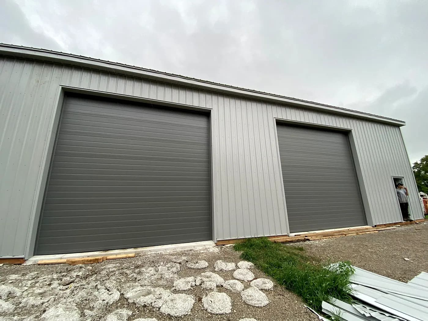 Steel-clad shop building with two large overhead doors and a gravel approach